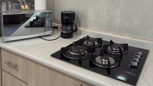 Een keuken met een gasfornuis, een magnetron en een koffiezetapparaat.