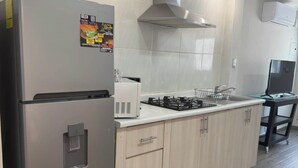Een moderne keuken met een roestvrijstalen koelkast, een gasfornuis en lichte houten keukenkastjes.