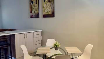 Een moderne keuken met een eethoek, voorzien van een tafel met stoelen, een hanglamp en twee aan de muur bevestigde schilderijen.
