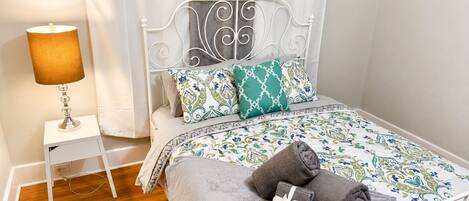 A neatly made bed with patterned bedding, a bedside lamp, and a small bedside table.