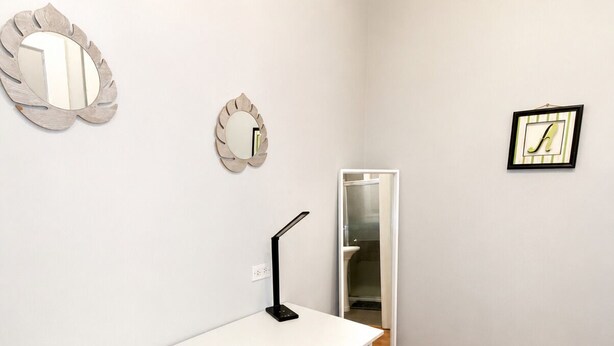A white desk with a chair, a mirror, and a framed picture on the wall. - Charming Downtown Studio - Walk to Toyota Center (Houston)