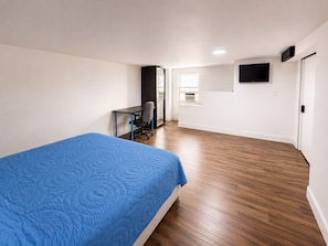 A bedroom with a bed, a desk, a chair, a television, and a window. - Spacious Studio Near Boston--Parking--Washer/Dryer (Everett)