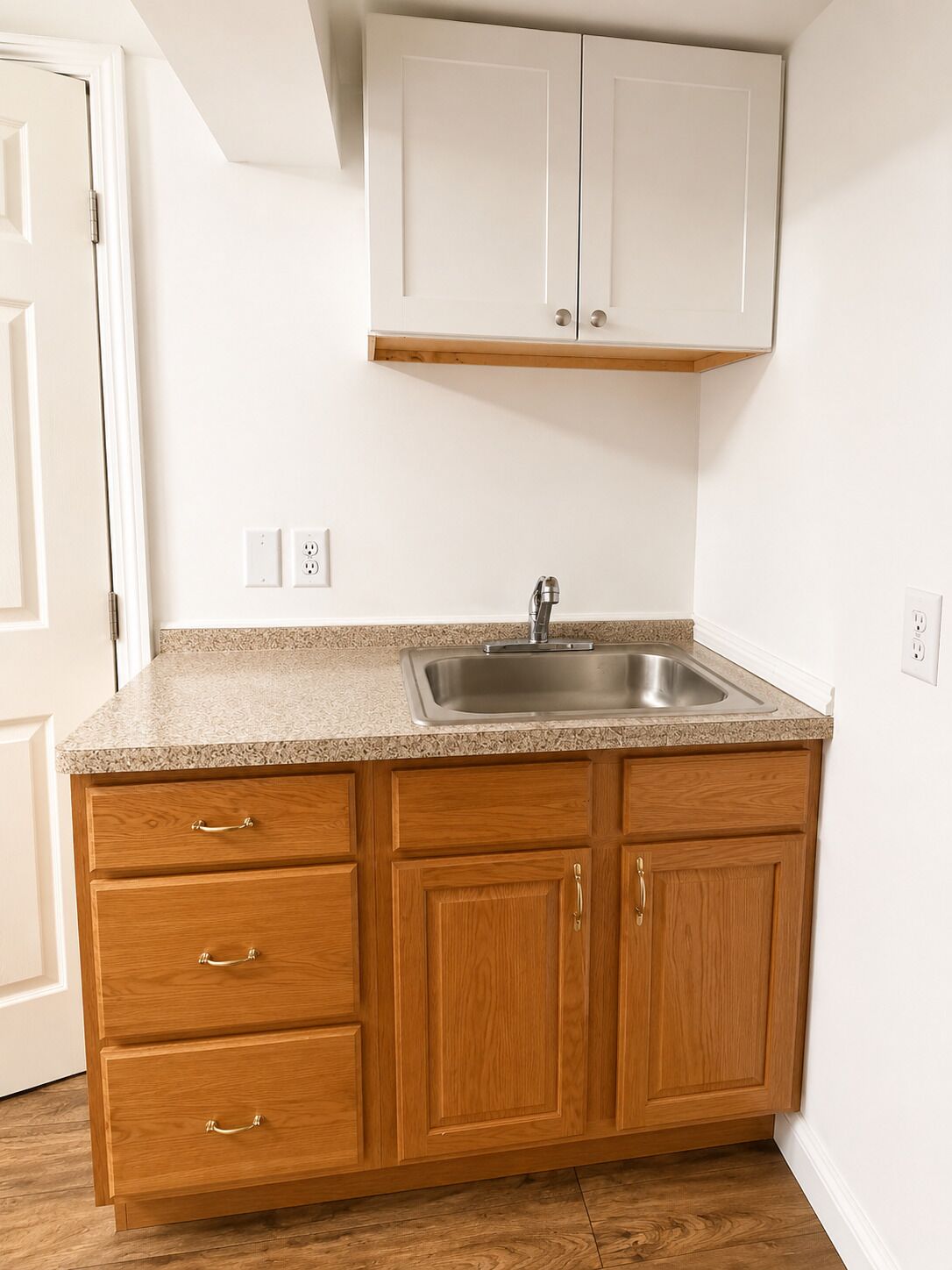 A kitchen with a granite countertop, wooden cabinets, a stainless steel sink, and a white ceiling.