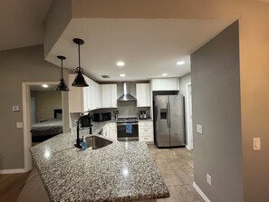 A modern kitchen with granite countertops, stainless steel appliances, and pendant lighting. - 3-bedroom house near Brownwood • Pet Friendly (Wildwood)