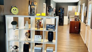 A hotel lobby with a central white shelving unit displaying various items, a wooden floor, and a reception desk in the background. - Fantastic 2-bedroom house with AC in sunny Los Angeles (Los Angeles)