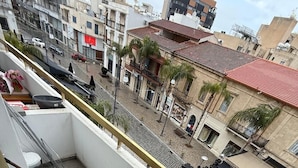 Un balcone con una sedia, un secchio blu e un tavolo.
