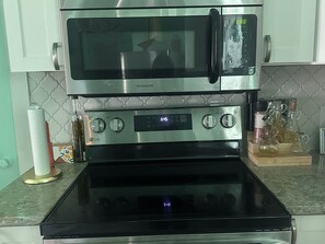A kitchen with a stainless steel microwave, oven, and a digital clock displaying 6:45. - Perfect 4-bedroom house with AC in quaint Aransas Pass (Aransas Pass)
