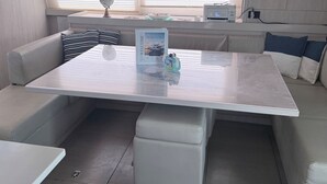 Un interior moderno con una zona de estar central, una mesa de comedor y un rincón de cocina.