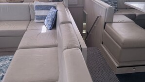 Interior de barco con un sofá, una mesa y un globo terráqueo en una estantería.