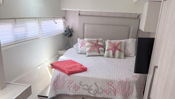 Un dormitorio con cama, mesitas de noche, televisor y una puerta.