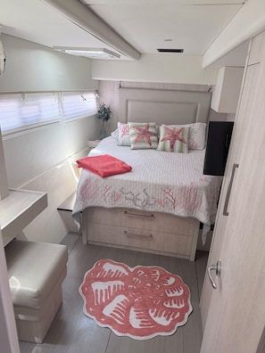 A bedroom with a bed, bedside tables, a TV, and a door. - 3-bedroom catamaran with pool and beach access in amazing Key West! (Key West)