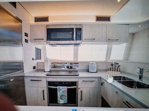 A compact kitchen with a microwave, oven, and dishwasher. - 3-bedroom catamaran with pool and beach access in amazing Key West! (Key West)
