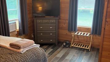 A bedroom with a bed, a TV, a dresser, and a ceiling fan.