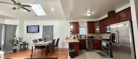 Una cocina moderna con una isla central, electrodomésticos integrados y un comedor con mesa y sillas.