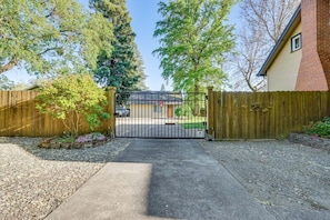 A gated driveway leading to a house with a brick exterior and a wooden fence. - Grants Pass Retreat Across from Riverside Park! (Grants Pass)