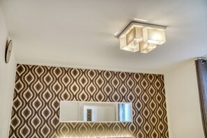 A room with a patterned wallpaper, a rectangular mirror, and a ceiling light fixture. - located in heart of bolton town, 2 minutes walk from bus station&trainstaion (Bolton)