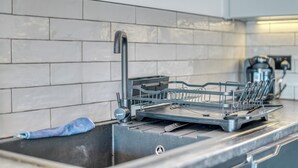 Cuina amb escorredor, aixeta i cafetera.