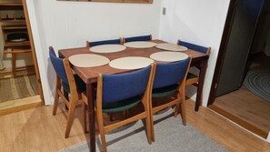 A dining table with six chairs, a wooden floor, and a carpeted area.