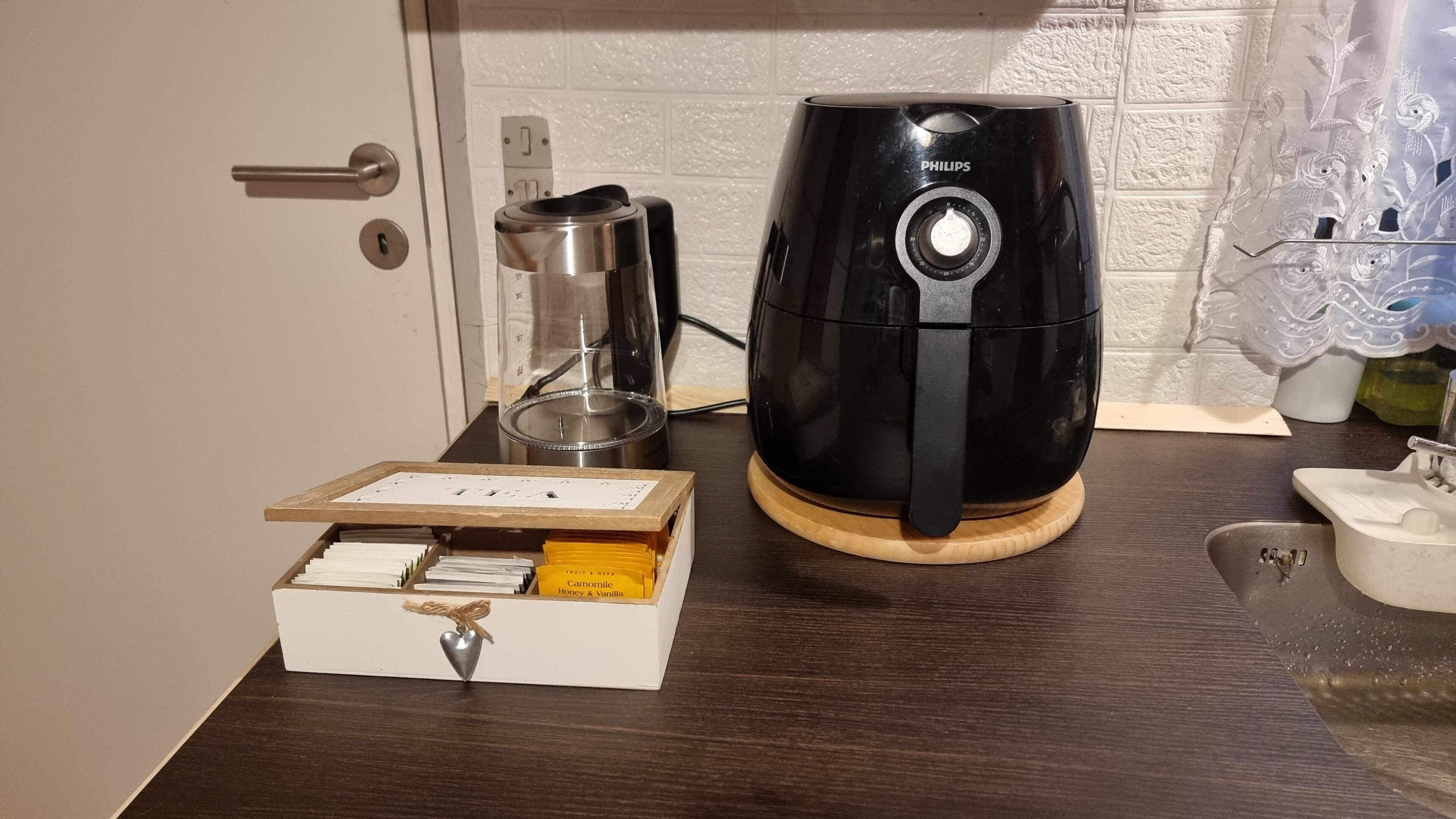 A coffee maker, a glass carafe, and a drawer with a heart-shaped ornament on a wooden countertop.