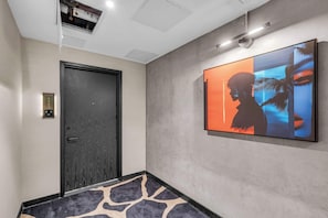 Um corredor com uma porta, uma obra de arte na parede e um tapete estampado.