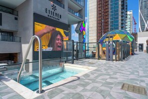 A swimming pool area with a glass barrier, a large advertisement for a marathon, and a colorful structure. - Skyline Miami & Resort Amenities (Miami)