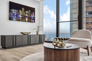 A modern living room with a cityscape view, a grey console table, a round coffee table, and a white armchair. - Skyline Miami & Resort Amenities (Miami)