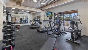 Un gimnasio con cintas de correr, elípticas y equipo de levantamiento de pesas.