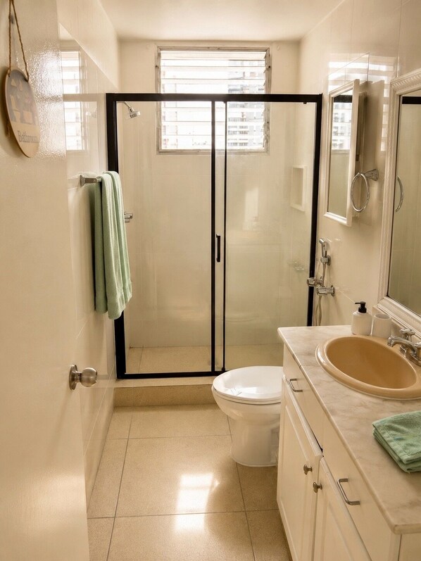 Une salle de bain avec une douche à parois de verre, des toilettes, un lavabo et un miroir.