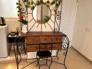 A wooden vanity with a mirror, a small stool, and a vase with flowers. - HOME PANAMÁ  (Panama City)