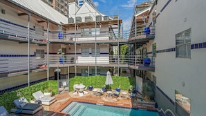 Un espace extérieur doté d’une piscine à plusieurs niveaux, de chaises longues et d’une petite table.