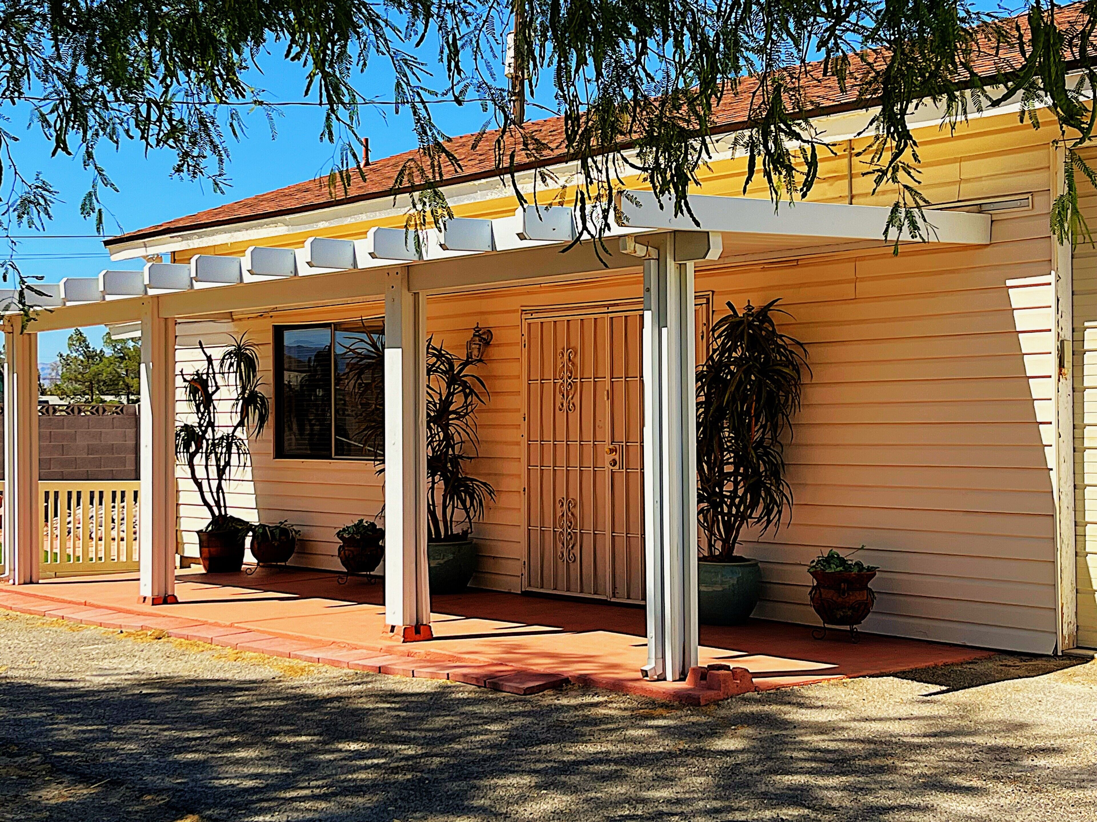 A house with a covered porch, potted plants, and a wooden door.
