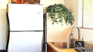Uma cozinha com geladeira, pia e janela com persianas.