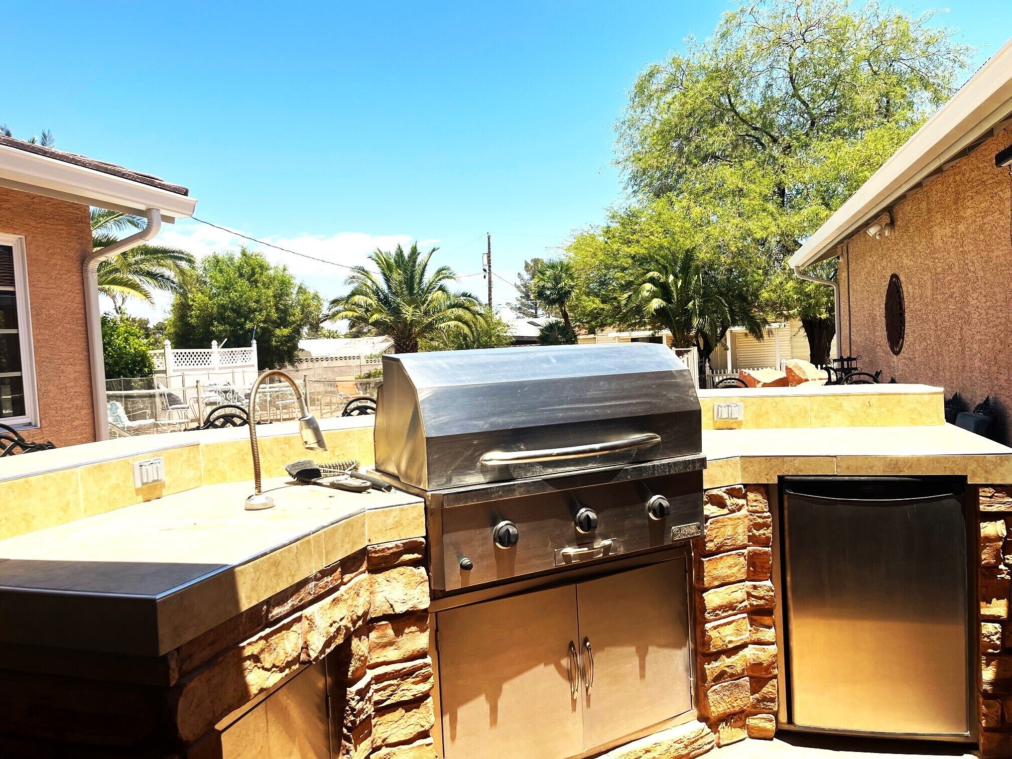Cocina exterior con parrilla, fachada de piedra y lavavajillas.