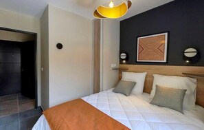 A hotel room with a bed, a headboard, a wall-mounted artwork, and a door leading to another room. - Wifi, 100m from ski slopes, swimming pool, sauna, hammam, balcony, tv, ski locker, 42m², Auron (Auron)