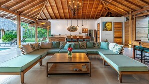 A spacious living area with a wooden ceiling, a large sofa, a coffee table, and a dining area. - Casa la Onda "Ultra" Suite (Provincia de Puntarenas)
