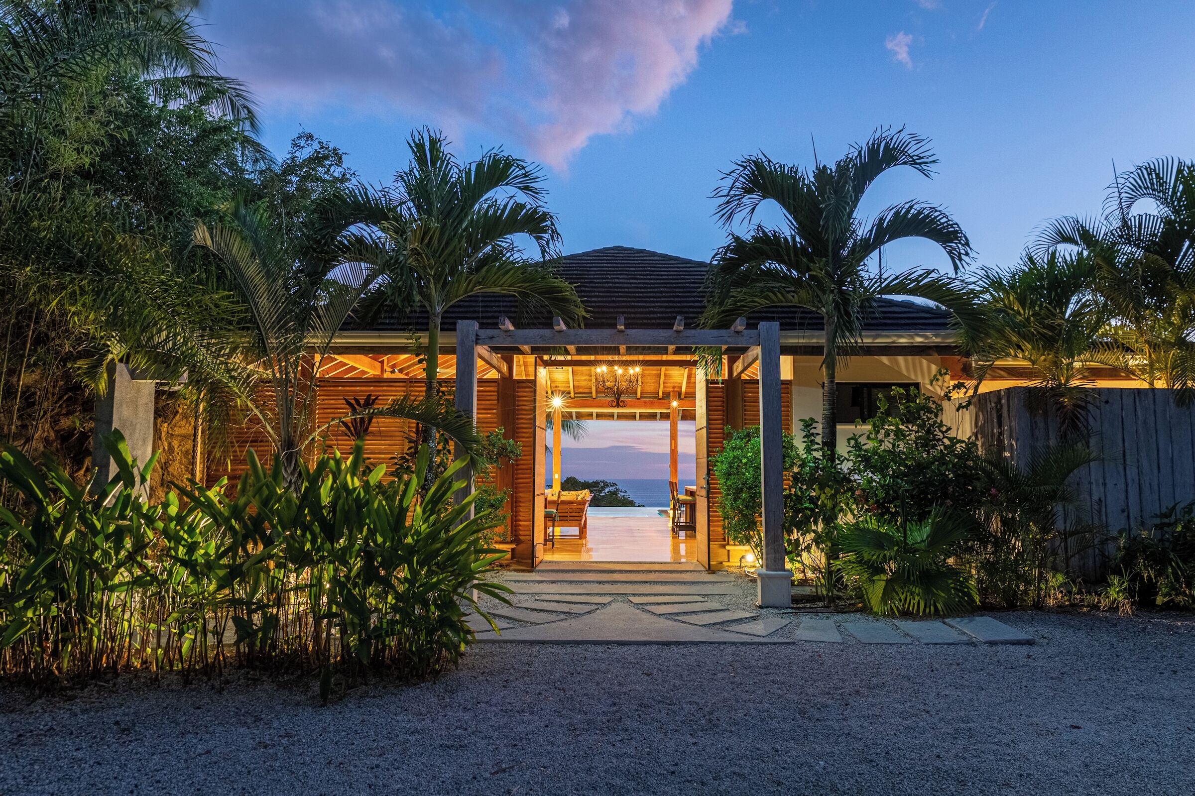 A resort with a covered entrance, palm trees, and a view of the ocean.
