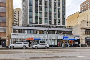 A multi-story building with a modern facade, a restaurant with a visible menu, and a parking area with cars. - Industrial-Style Cityscape 1 Bedroom Loft (Edmonton)
