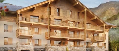 A multi-story wooden building with balconies, stone foundation, and a mountainous backdrop.