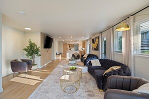 Una sala de estar moderna con un sofá, sillones, una mesa de centro, un televisor y una planta en maceta.