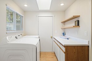 Un cuarto de lavandería con lavadora, secadora, una encimera de madera y una puerta.