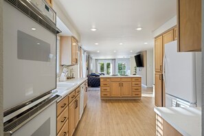 Une cuisine moderne avec des meubles en bois, un îlot central et un grand réfrigérateur.