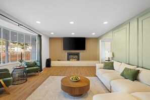 Ein modernes Wohnzimmer mit Kamin, großem Fenster und einer Couch.