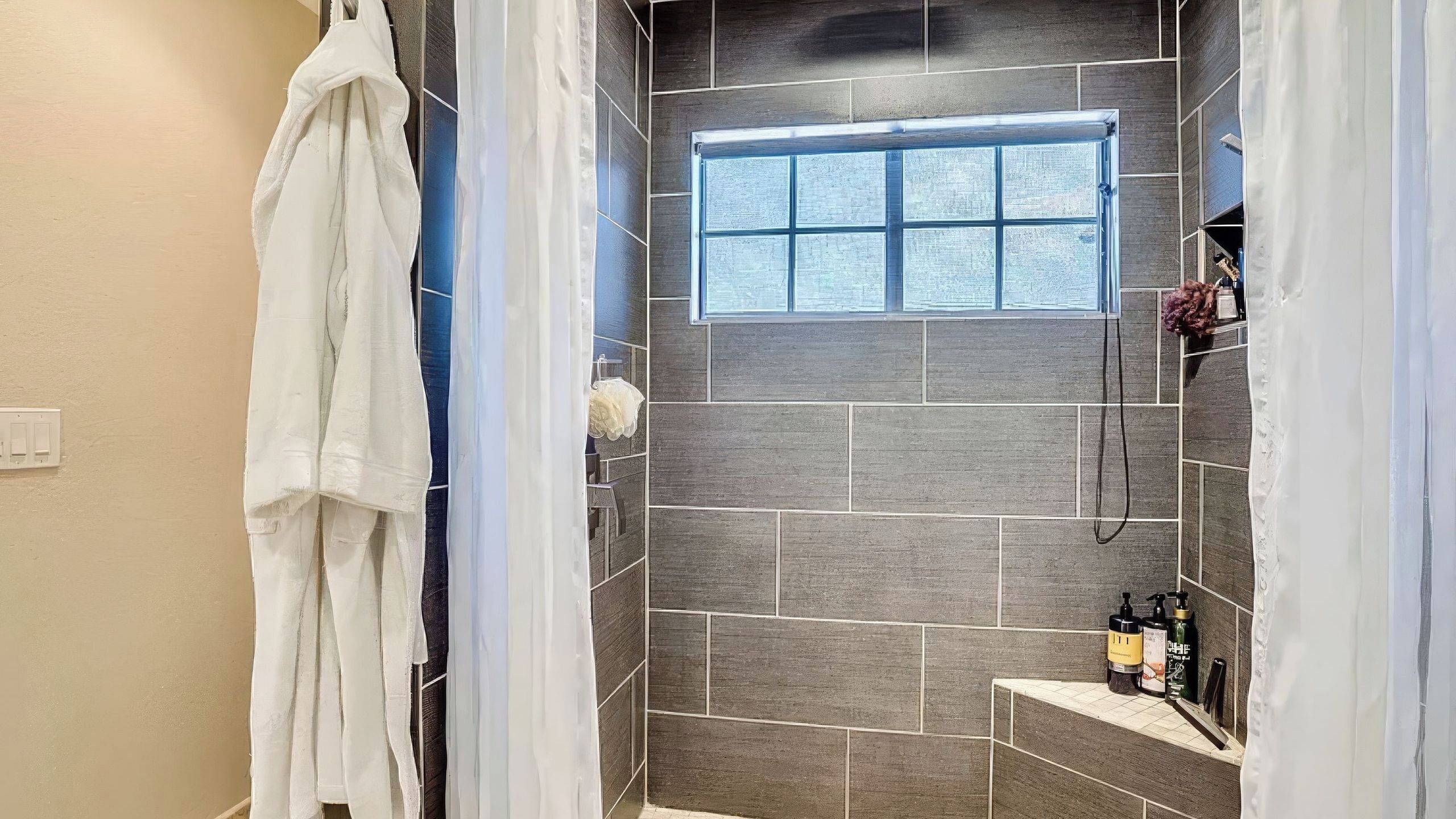 Eine Dusche mit Fenster, gefliesten Wänden und einem Handtuchhalter.