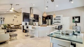 A modern kitchen with a central island, bar stools, and pendant lighting. - Endless Summer Oasis by Avantstay Private Pool + Hot Tub + Putting Green Rooftop + Near Golf (Scottsdale)