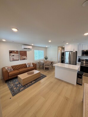 A modern kitchen with stainless steel appliances, a dining area with a round table and chairs, and a living area with a brown sofa and a coffee table. - Spacious 4-bedroom townhome in delightful Los Angeles with AC (Los Angeles)