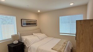 Een slaapkamer met een bed, nachtkastje en een houten garderobe.