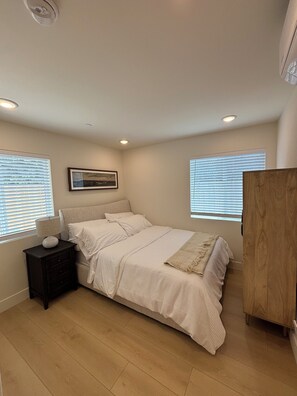 A bedroom with a bed, nightstand, and a wooden wardrobe. - Spacious 4-bedroom townhome in delightful Los Angeles with AC (Los Angeles)