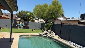 A swimming pool with a rock feature, a sign reading 'WESTGATE,' and a fenced yard with grass and trees. - Beautiful 3-bedroom house with pool & game room in charming Glendale (Glendale)