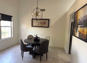 A dining area with a round table, chairs, a chandelier, and artwork on the walls. - Beautiful 3-bedroom house with pool & game room in charming Glendale (Glendale)