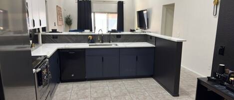A modern kitchen with a central island, built-in appliances, and a large window.